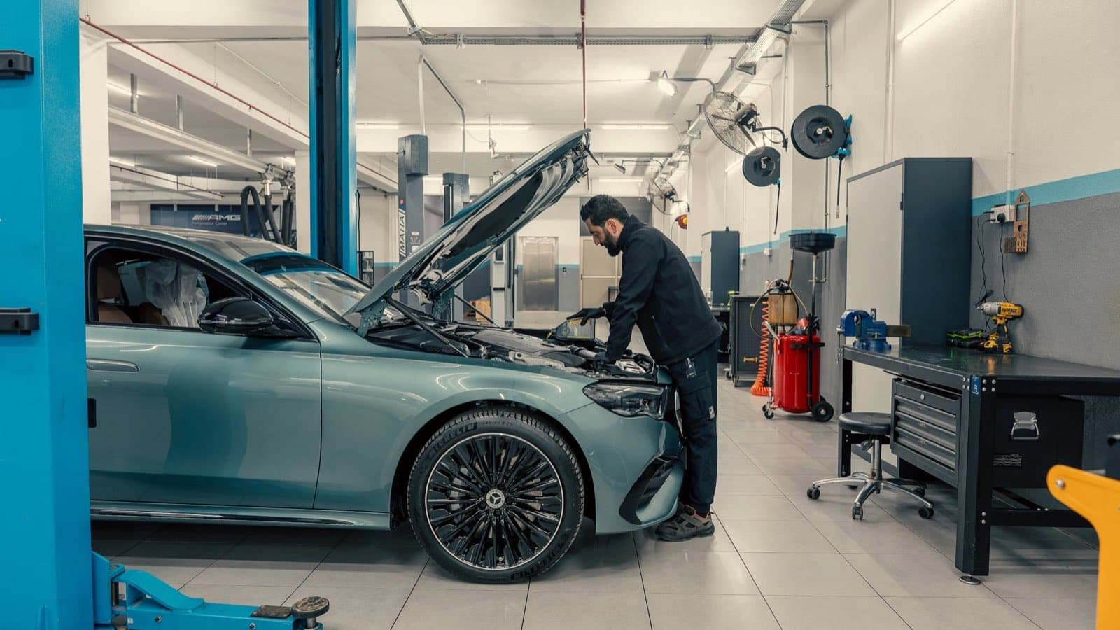 Technicien penché sous le capot d'une Mercedes Classe E récente dans un atelier de concession