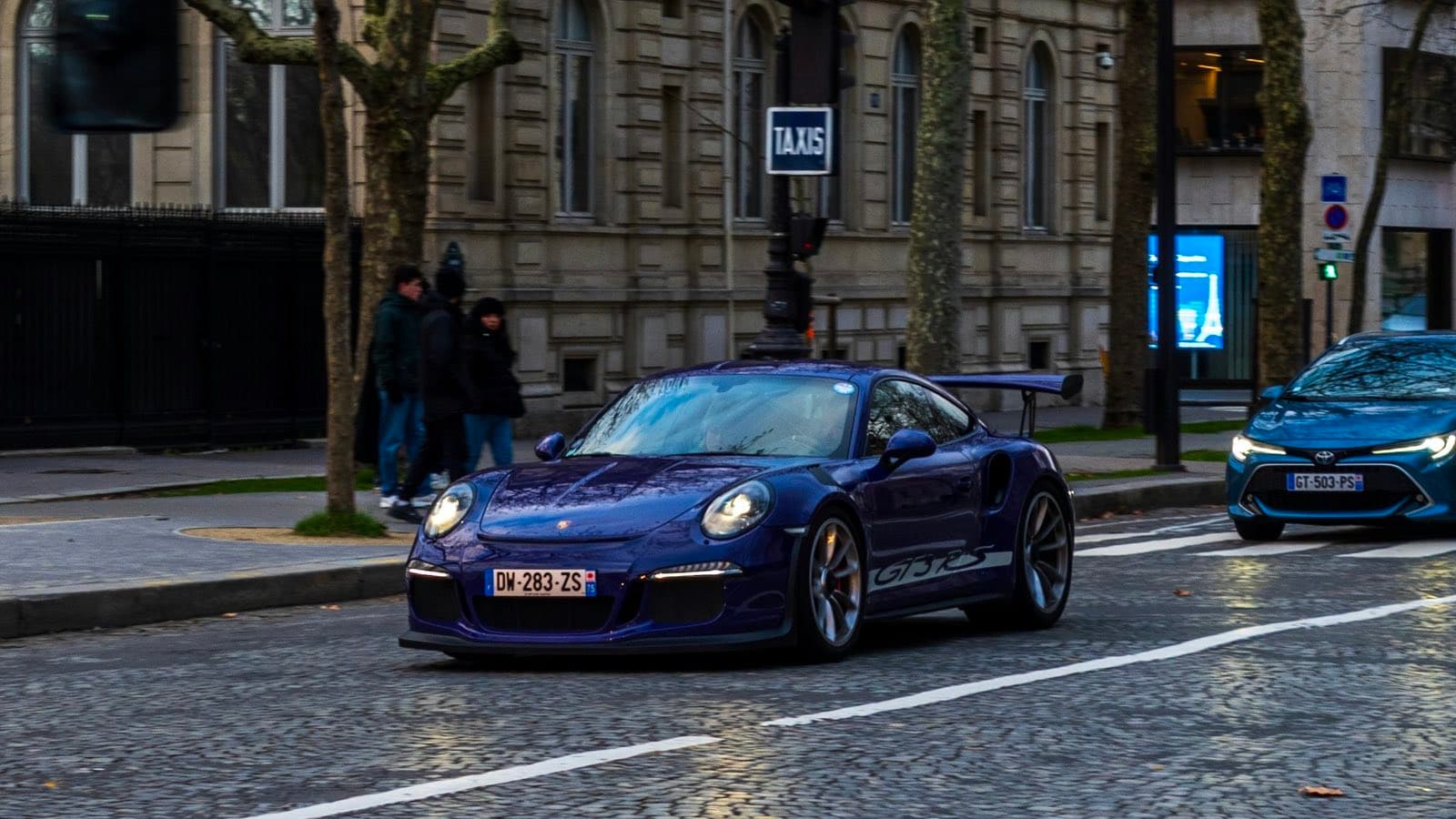 Porsche 911 GT3 RS circulant sur les pavés d'une avenue parisienne