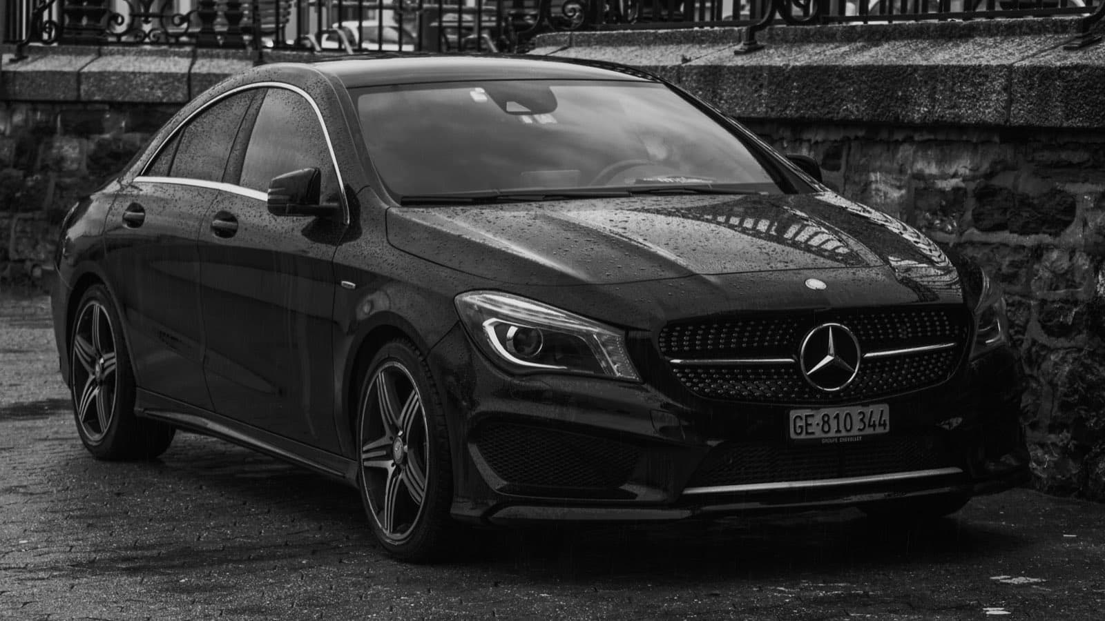 Black Mercedes registered in Geneva, GE plate, parked on wet cobblestones